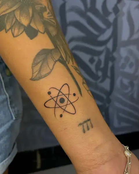 Tatuagem fine line de átomo no antebraço