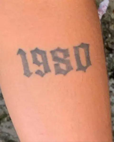 Tatuagem antiga com o número 1980, antes da cobertura