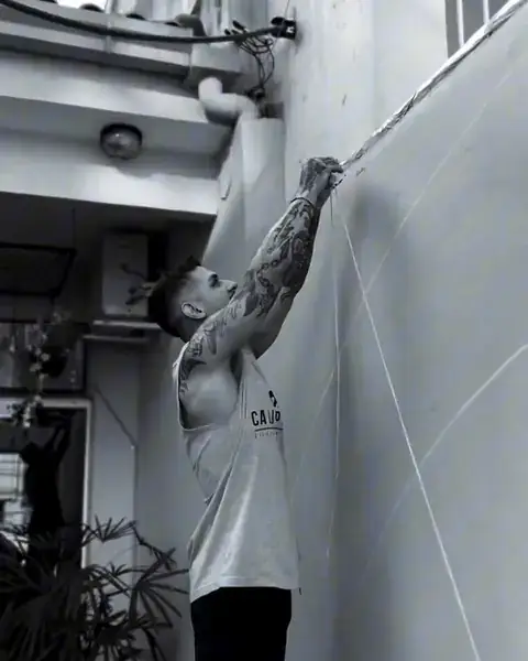 André Loureiro marcando as linhas-guia na parede antes de pintar o calligraffiti