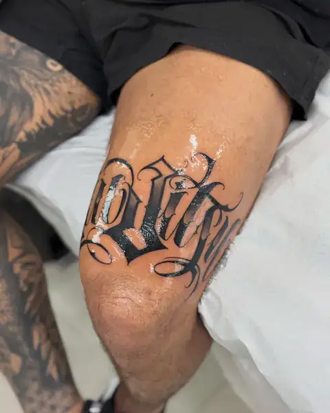 Custom lettering “Jiu-jitsu” tatuado acima do joelho