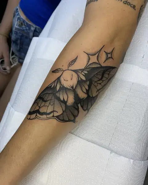 Tatuagem neotradicional de mariposa com estrelas no antebraço