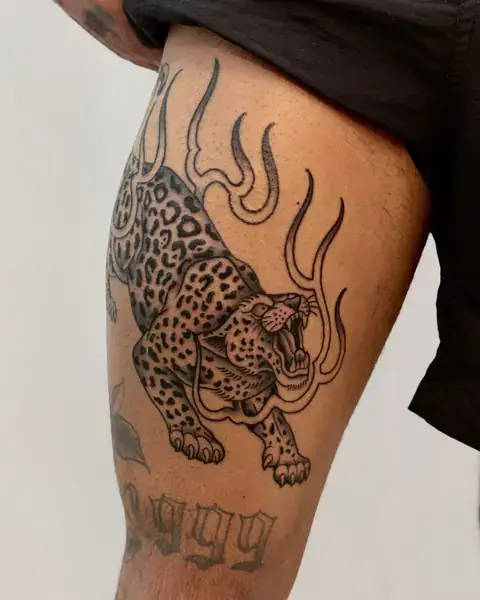 Tatuagem old school de onça com chamas na coxa